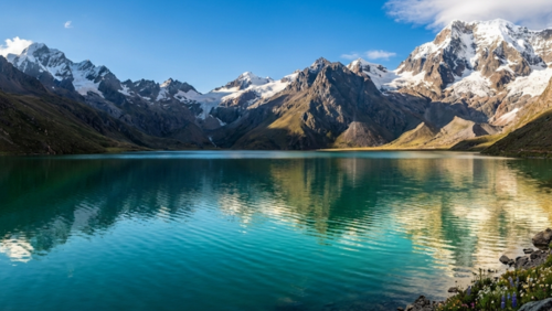 高原のエメラルドグリーンの湖、周囲の山々と空が湖面に映る景色。人物なし。