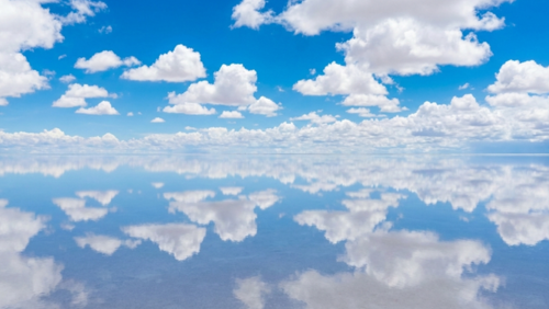雨季のウユニ塩湖、水面が鏡のように空と雲を映す幻想的な景色。人物なし。
