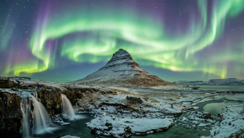 夜空に広がるオーロラが光のカーテンのように舞うアイスランドの夜景