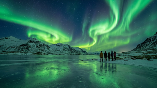 アイスランドの夜空に広がるオーロラ。雪に覆われた山と凍った湖の上で、緑色の光のカーテンが揺らめく幻想的な観測風景