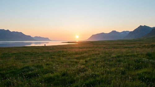 アイスランドの夏、深夜でも地平線近くに太陽が残り、空と大地が淡いオレンジと青に染まる白夜の風景