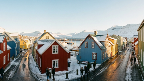 アイスランドのカラフルな家々が並ぶ街並み、冬の雪と石畳の通り、住民や観光客が散策している様子