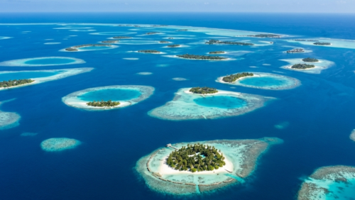 約1,200の小さな島々からなるモルディブの群島を空から見た景色。点在する環礁とターコイズブルーの海が広がる
