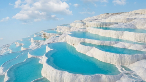 トルコのパムッカレに広がる白い石灰棚の絶景。温泉の石灰成分が長い年月をかけて堆積し、真っ白な段々の地形と青い温泉水が美しい景観を作っている。