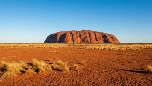 オーストラリア中央部の広大な赤い砂漠の中で、遮るもののない水平線の中にウルルが単独でそびえ立つ風景