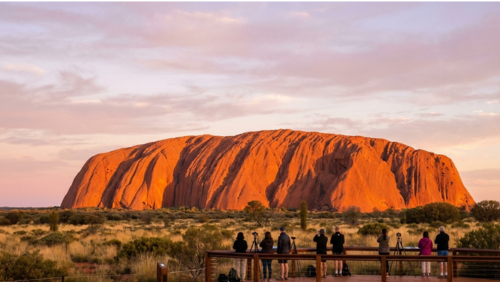 サンライズ展望台から朝日に照らされて赤く輝くウルルを眺める風景