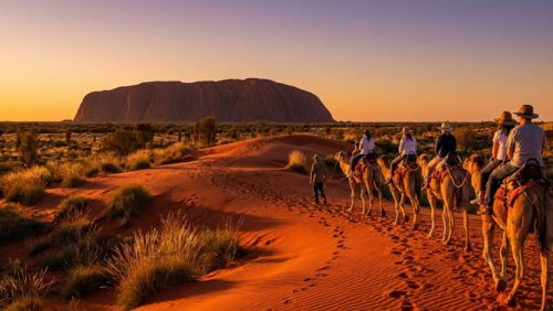 オーストラリア中央部の赤い砂漠でラクダに乗って移動するキャラバンの風景
