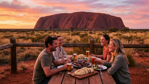 ウルルと赤砂漠を一望できる展望台の屋外テーブルで、景色を眺めながら食事を楽しむ様子
