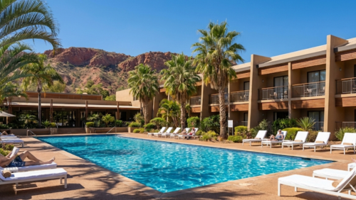 赤いマクドネル山脈を背景に、プールとヤシの木に囲まれたダブルツリー・バイ・ヒルトン・アリス・スプリングスのリゾート外観