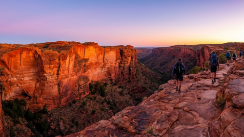 早朝のキングスキャニオン・リムウォークで朝日を浴びながら断崖の上を歩くハイカーの風景