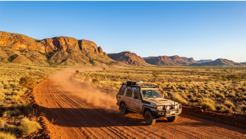 キンバリー地区の赤い大地の未舗装道路を走る四輪駆動車と、広大な秘境の風景。