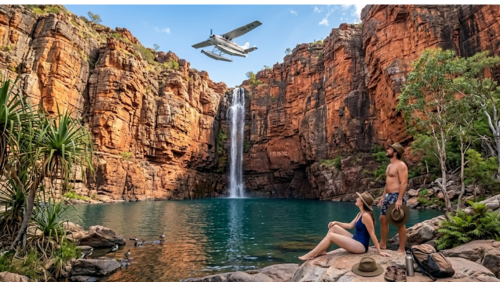 オーストラリアのカカドゥ国立公園にある壮大な「ジムジム滝（Jim Jim Falls）」の風景写真です。数百フィートある巨大で赤褐色の砂岩の絶壁から、垂直に落ちる滝がエメラルドグリーンの深く澄んだ滝つぼへと注いでいます。前景の滑らかな岩場には、水着姿でリラックスしているカップル（男性と女性、二人ともアクーブラハットを着用）が座り、滝と、巨大な絶壁の上空を低空飛行する水上飛行機（セスナ機 VH-HFA）を見上げています。彼らの隣の岩にはアクーブラハット、サンダル、バックパックが置かれています。滝つぼの周りにはネイティブな植物（パンダナス、ユーカリ、シダ）が生い茂り、巨大な絶壁の質感と、上空の青空と飛行機が、秘境の冒険心を掻き立てる超高解像度画像です。