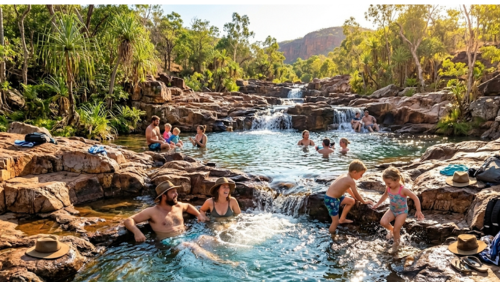 リッチフィールド国立公園にある「ブーリー・ロックホール」の賑やかな風景です。赤褐色の砂岩が階段状に連なり、無数の小さな滝とエメラルドグリーンの滝つぼが段々畑のように続いています。前景では、アクーブラハットを被ったカップルが天然のジャグジーのようなプールに浸かって笑い合い、そのすぐ隣では小さな男の子と女の子が水しぶきを上げて楽しそうに遊んでいます。背景の上の段にあるプールにも、多くの家族連れが思い思いにリラックスしている様子が写っています。周囲は緑豊かな熱帯雨林に囲まれ、夕暮れ時の柔らかな光が水面と人々の笑顔をキラキラと照らしている、幸福感に満ちた超高解像度8K画像です。