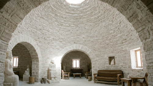 ウユニ塩湖近くの塩のホテルにある、塩で作られたドーム状の天井。塩ブロックの質感がはっきり分かるアーチ構造と、落ち着いた雰囲気の内観。