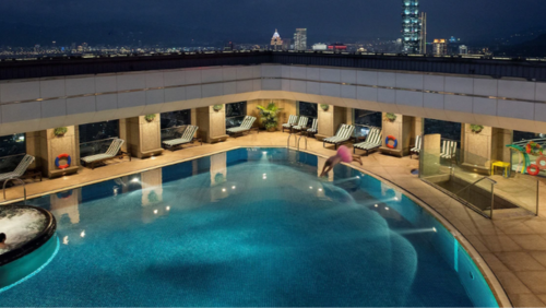 シャングリ・ラ ファーイースタン 台北の屋上にある季節限定屋外プール。ライトアップされた青い水面が美しく、プールの周りにはデッキチェアが並んでいる。背後には台北101をはじめとする高層ビル群の夜景が広がり、都会のオアシスのような開放感あふれる空間