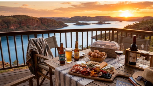 アーガイル湖を見下ろすリゾートのプライベートテラスで楽しむ、贅沢なアペリティフと朝食のセット。木製のテーブルには、冷えたクラフトビールと赤ワイン、生ハムやチーズ、ナッツ、ドライフルーツを盛り合わせた豪華なプラッター、そしてカゴに入った焼きたてのクロワッサンが並んでいる。背景には、黄金色の夕陽が湖面を照らし、島々がシルエットとなって浮かぶ広大なパノラマ絶景が広がる風景写真