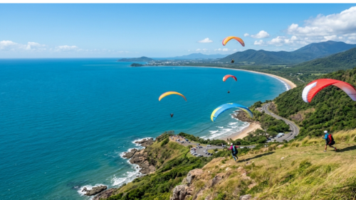 ケアンズの絶景スポット「レックス・ルックアウト」から見下ろす青い海と海岸線。空にはカラフルなパラグライダーが舞う風景